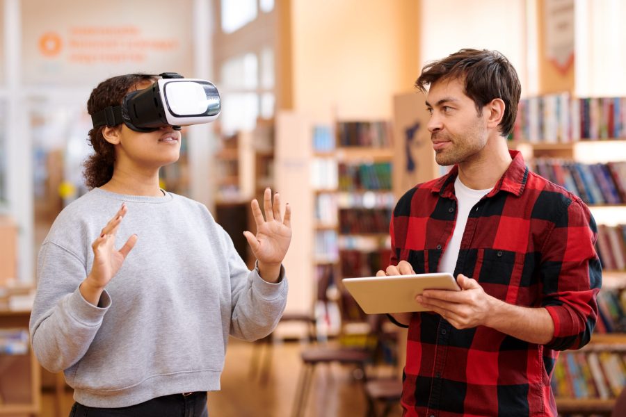 Young man with tablet interacting with his classmate in vr headset Augmented reality in Education